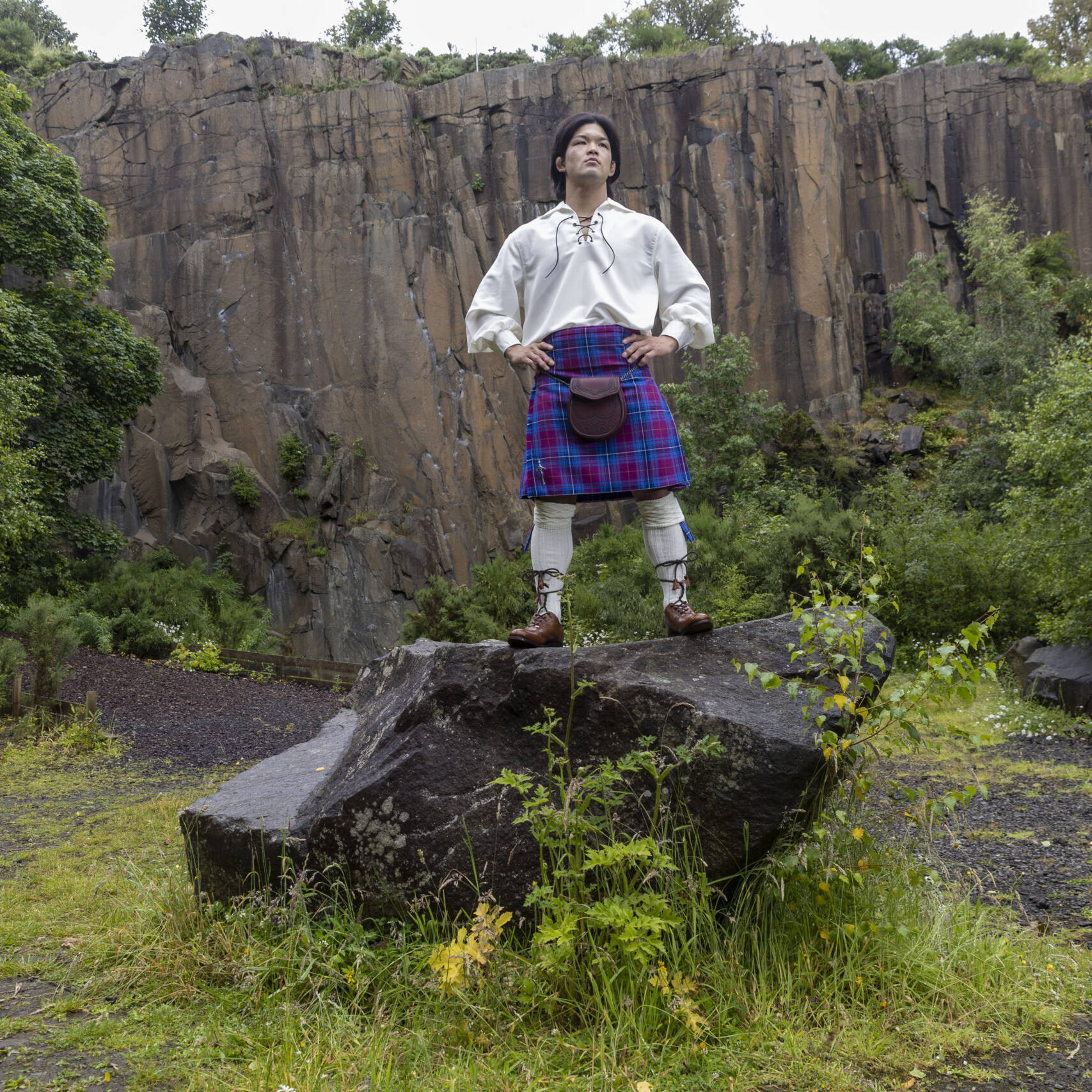 Ono standing on a rock in quarry wearing full Scottish Kilt outfit and JudoScotland kilt