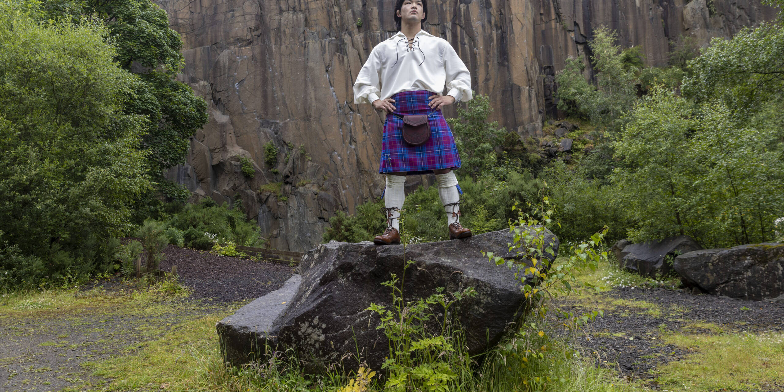 Ono standing on a rock in quarry wearing full Scottish Kilt outfit and JudoScotland kilt