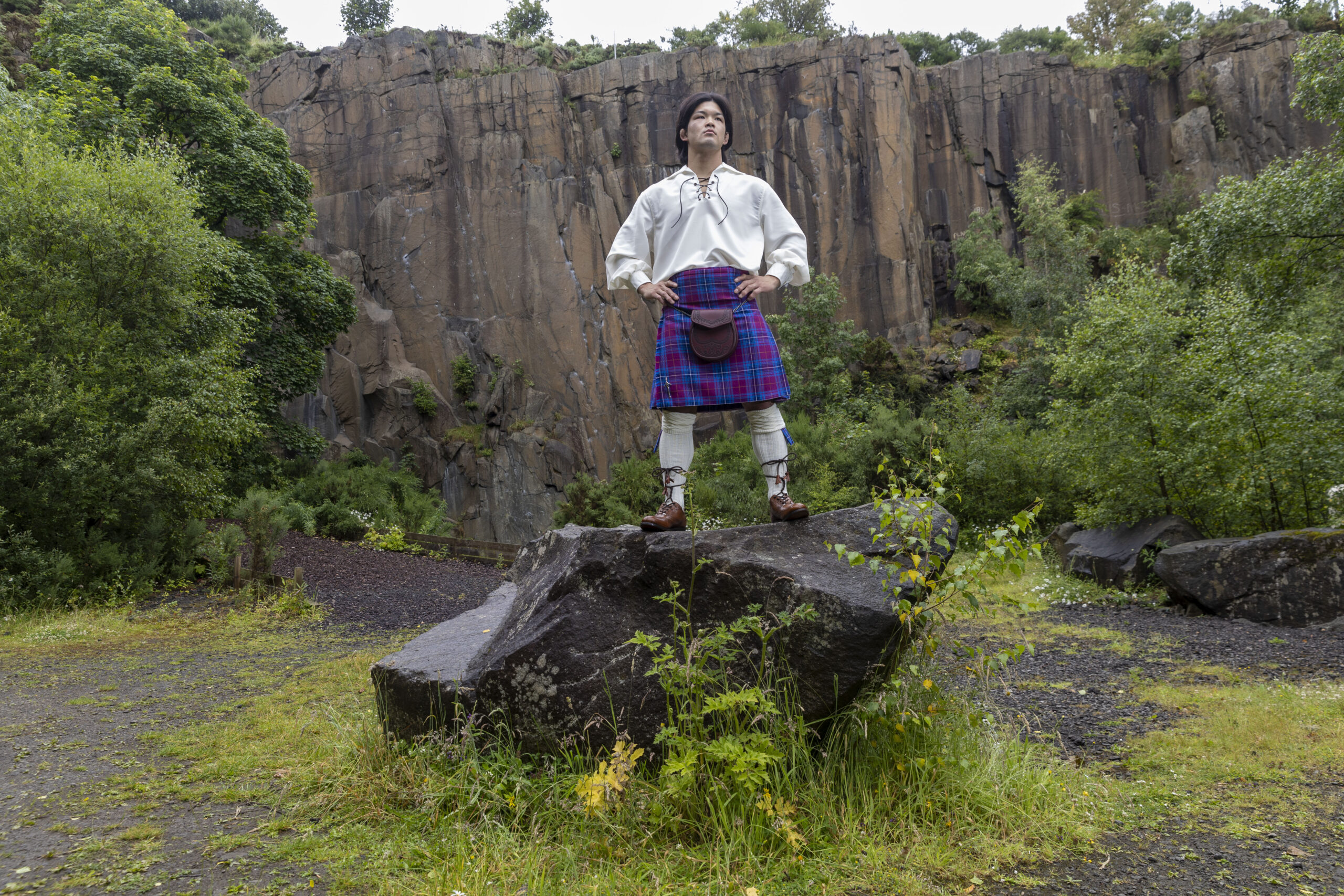 Ono standing on a rock in quarry wearing full Scottish Kilt outfit and JudoScotland kilt