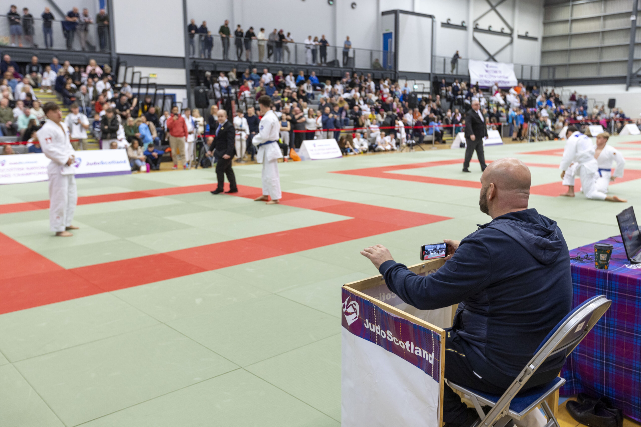 Field of play action shot featuring a coach giving instruction to a player on the mat via the coaching chair