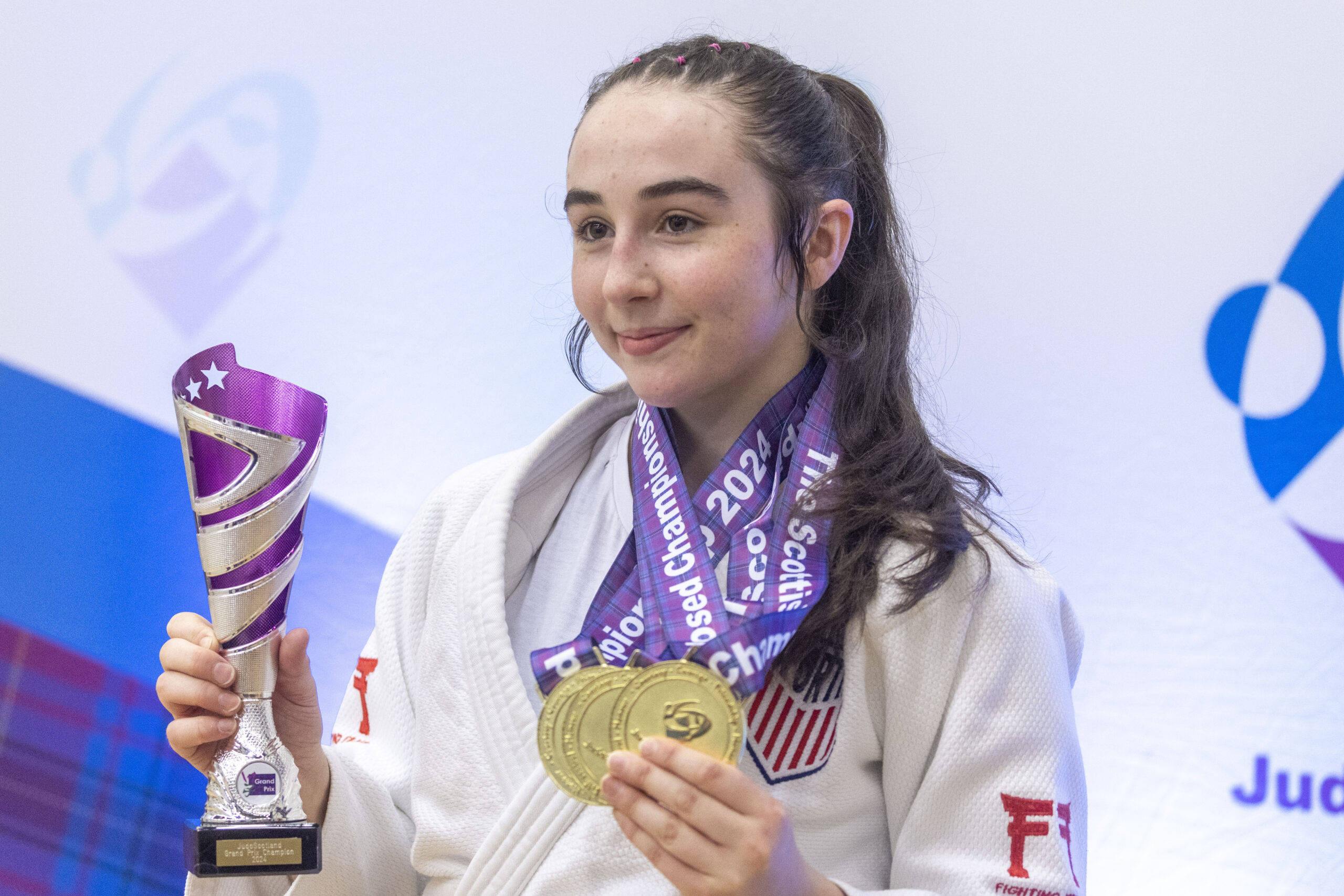 Maia Thomson holding her multiple medals and Grand Prix trophy